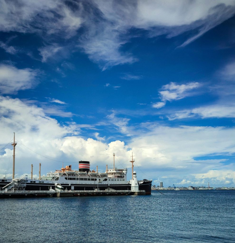 A cruise ship docked in Tokyo Bay on a clear day with vibrant blue skies and calm water.