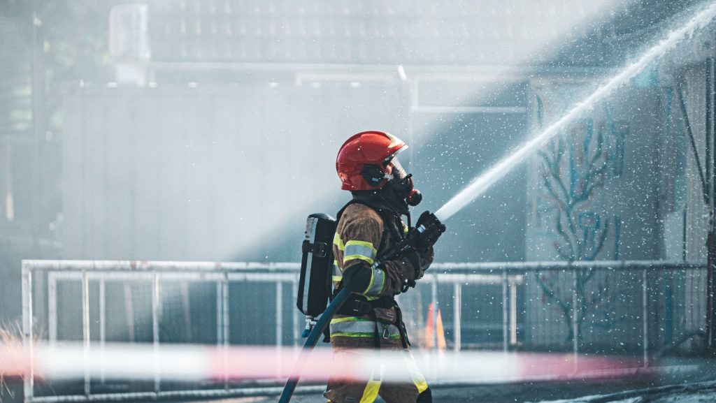 A brave firefighter operates a fire hose, wearing protective gear during a training exercise outdoors.
